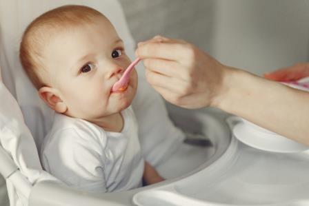 Mother feeds the little baby in a kitchen